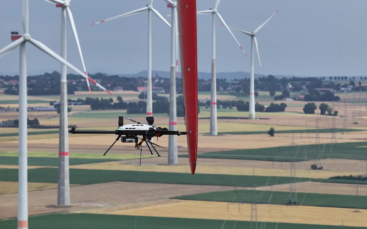 Voliro T Messdrohne im Einsatz an einem Rotorblatt, Windpark im Hintergrund